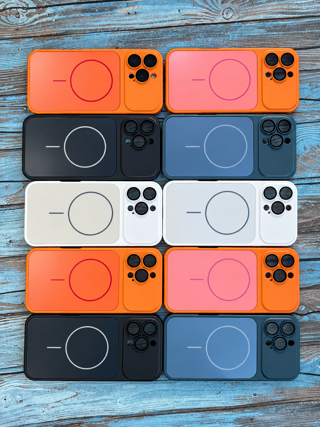 Twelve MagSafe-compatible phone cases arranged in a 4x3 grid on a rustic blue wooden background. The cases come in four colorways: vibrant orange, coral pink, matte black, and slate blue, with some cases showing the white interior side.