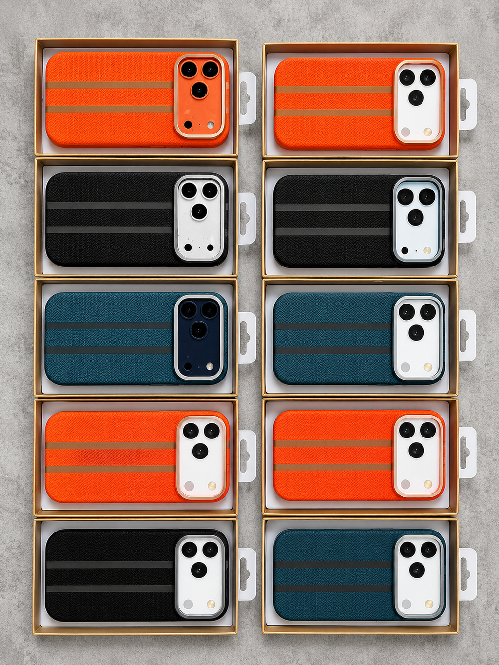 Twelve phone cases arranged in a 3-by-4 grid inside open retail boxes on a light gray textured surface. The cases come in three colorways: bright orange, black, and dark teal, each with two horizontal metallic stripe accents.